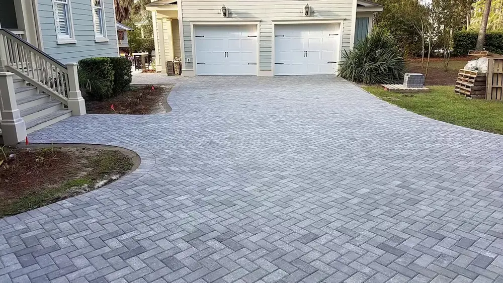 Gray herringbone paver driveway in front of a two-car garage