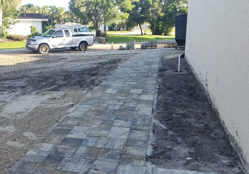 Paver walkway being installed along the side of a home