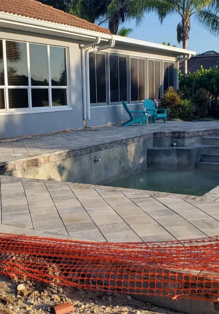 Paver pool deck installed around an in-ground pool next to a lanai