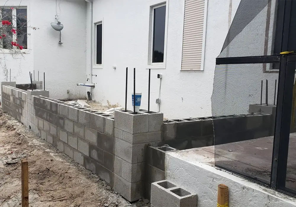 Block stem wall with vertical rebar dowels along an existing home