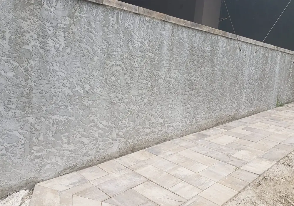 Finished stucco wall alongside a new paver walkway