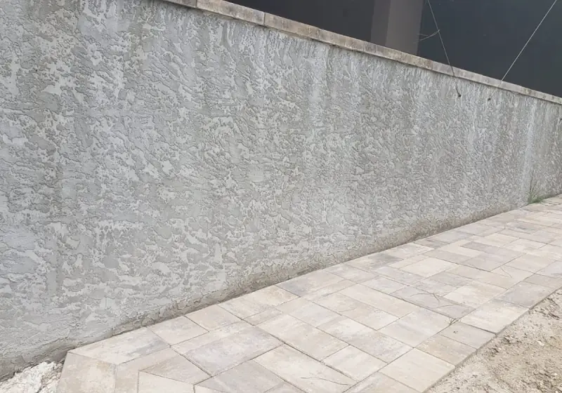 Finished stucco wall alongside a new paver walkway
